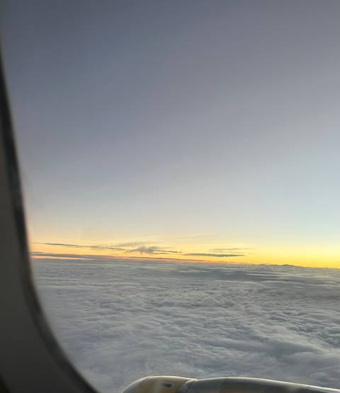 View of clouds from an airplane window during sunrise.