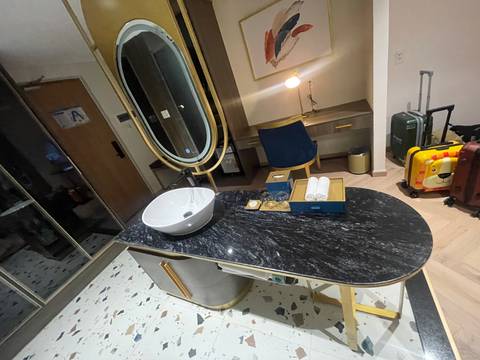       Hotel room with a sink, mirror, and suitcases in the background.
  