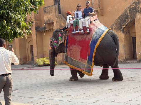       People riding an elephant with a guide taking pictures.
  