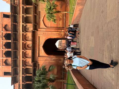 Woman standing in front of a large gate with a group of people.