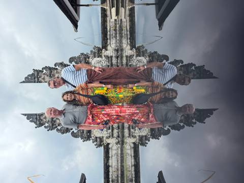 Group posing at a Balinese temple with reflections in water.