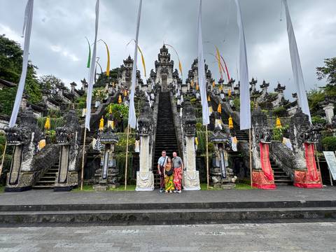 Two people standing at the steps of a large Balinese temple.