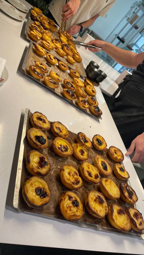 Baking pastries, possibly Portuguese custard tarts, on trays.