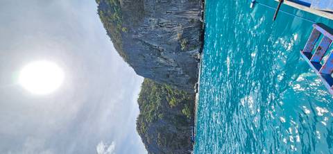 A sunny day with clear blue waters and steep rock formations.