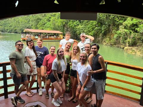 A large group of people on a boat with lush surroundings.
