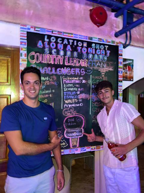 Two people standing in front of a colorful scoreboard.