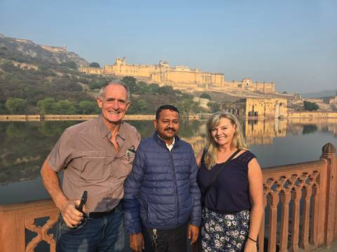 Three people posing with Amber Fort in the background