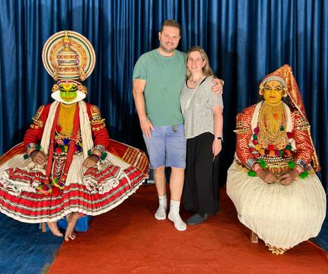       A couple posing with traditional dancers in elaborate costumes.
  