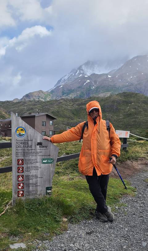       Person in winter clothing standing beside a Torres del Paine sign.
  