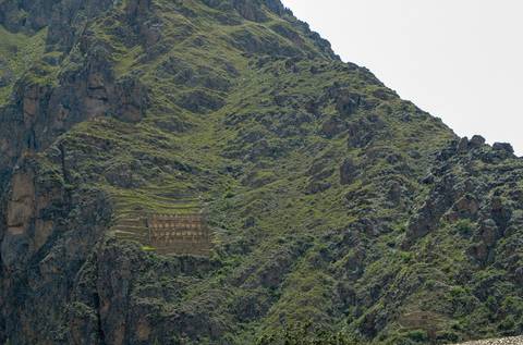Stone terraces built into a steep, green mountain slope.