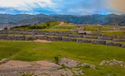 Extensive Incan ruins surrounded by mountains with people exploring.