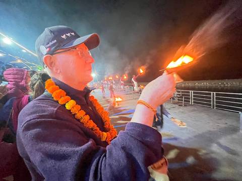 Person participating in a traditional river ceremony at night.