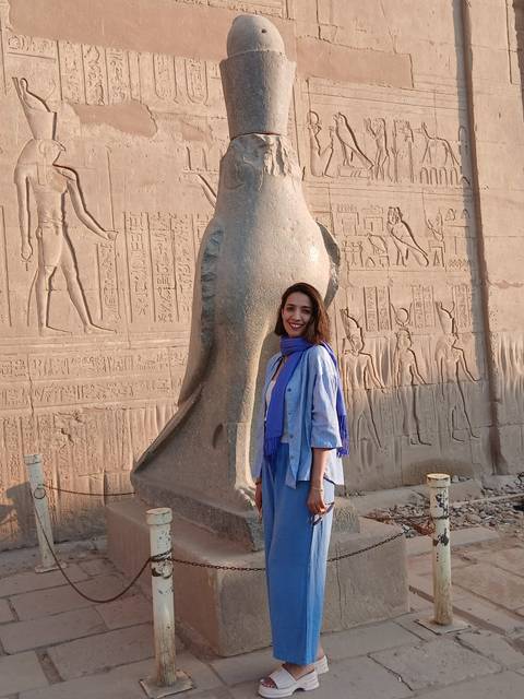       Woman posing with ancient Egyptian statues and hieroglyphs.
  