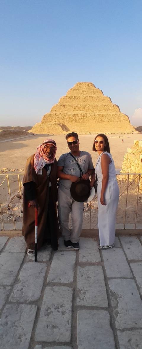       Two people posing with a guide in traditional clothing.
  