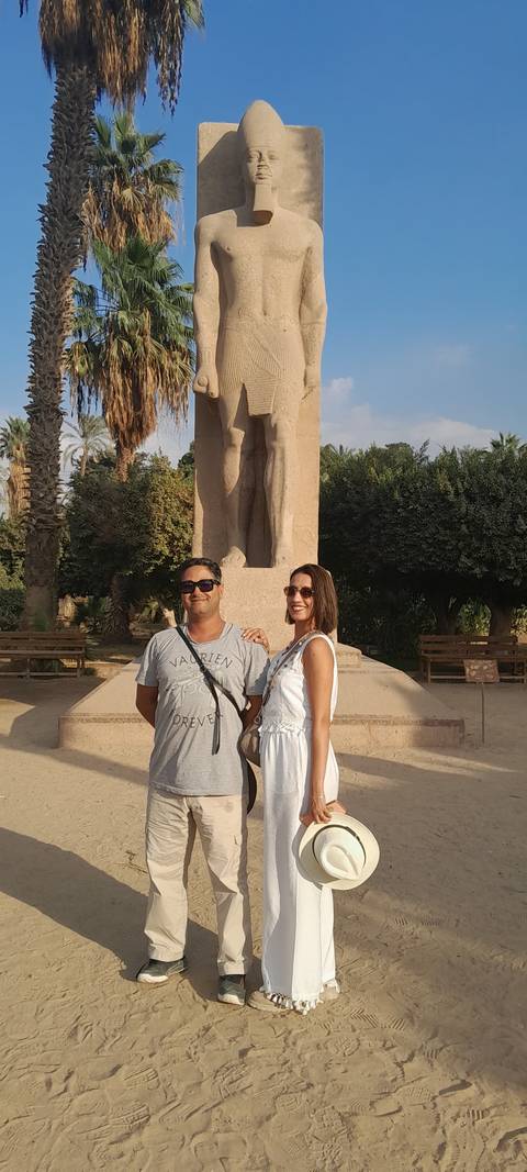 Man and woman posing in front of an ancient statue.