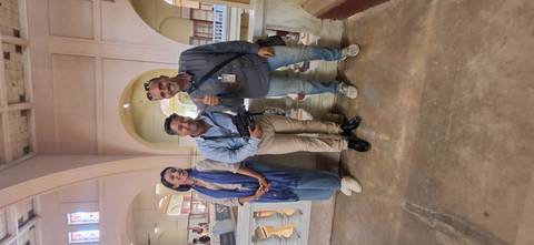       Three people posing inside a museum with architecture.
  