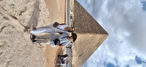       Couple posing in front of a pyramid with blue skies.
  