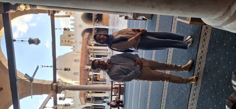       Two people inside a mosque with intricate decorations.
  