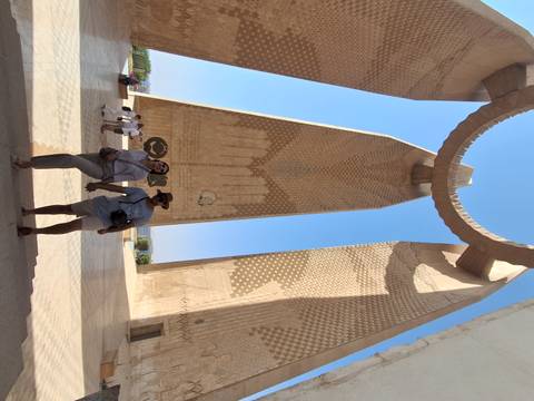       Couple holding hands under a large monument.
  