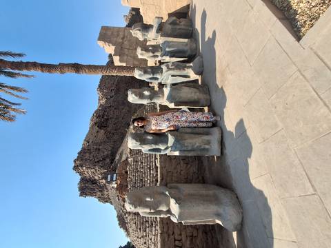       Woman standing with statues in an ancient ruin.
  
