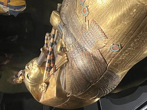 Golden sarcophagus with intricate designs in a display.