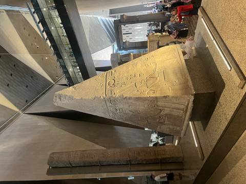       Ancient stone monument with hieroglyphs in museum setting.
  
