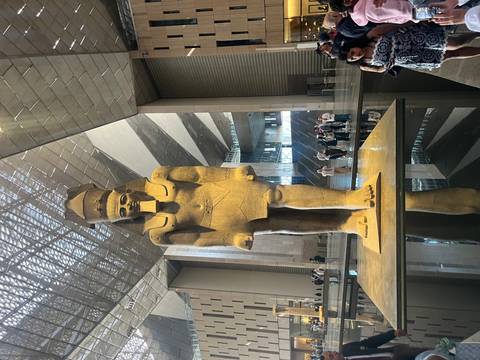       Tall statue of an ancient Egyptian figure in a spacious museum.
  