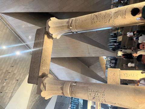 Ancient stone pillars inside a museum with visitors.