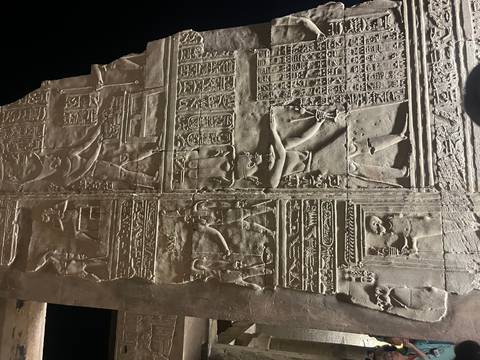 Carved stone panel with ancient figures in a museum.
