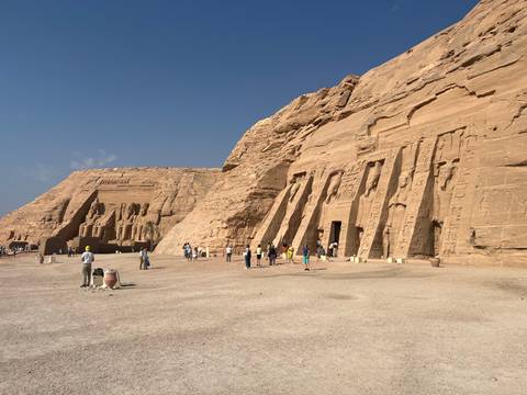       A group of tourists exploring large rock-carved ancient buildings.
  
