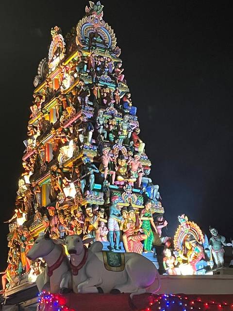       Ornate temple structure with numerous figures, illuminated at night.
  