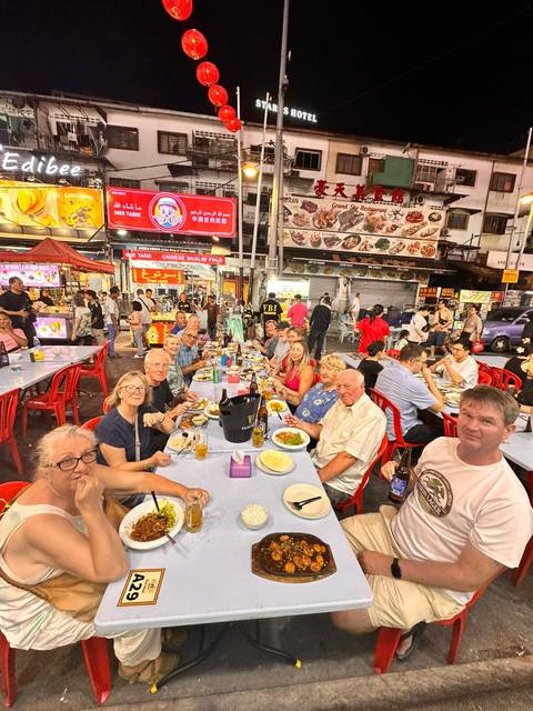 Group of people dining at a bustling outdoor food market at night.
