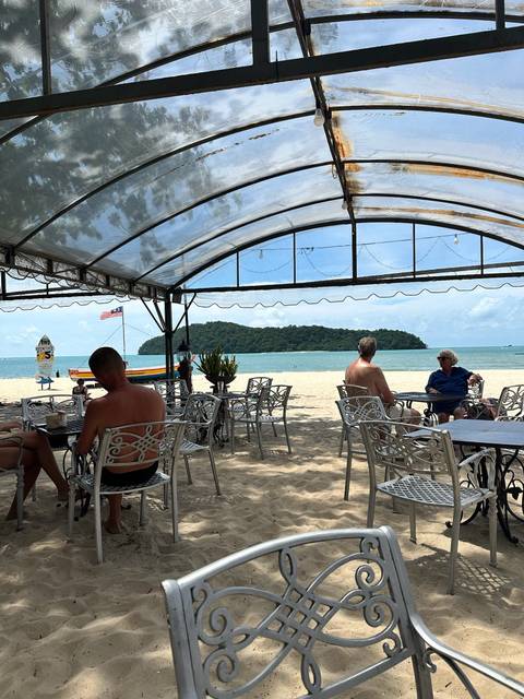 People relaxing at a beachside cafe with a view of the ocean.