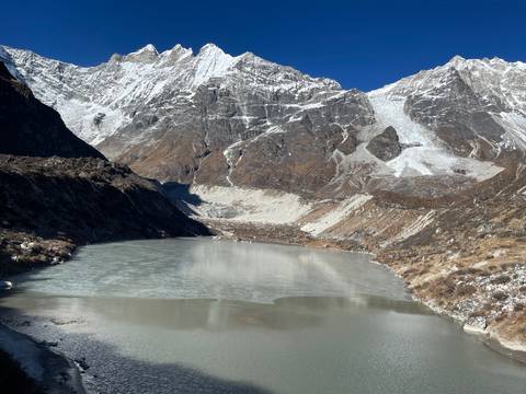       Frozen lake surrounded by snow-covered mountains.
  