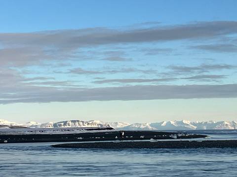 Snowy mountain range with a river in the foreground.