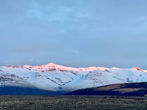 Snow-covered mountains with a pink hue from the setting sun.
