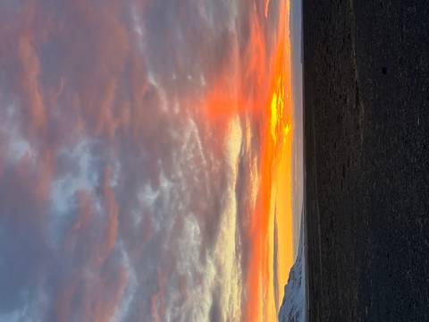 Sunset over a calm ocean with vibrant orange and pink skies.