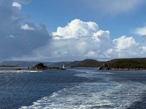       Scenic view of a lighthouse on an island surrounded by mountains.
  
