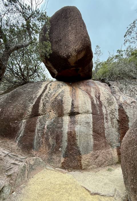       A large rock with colorful striations set against a dramatic backdrop.
  