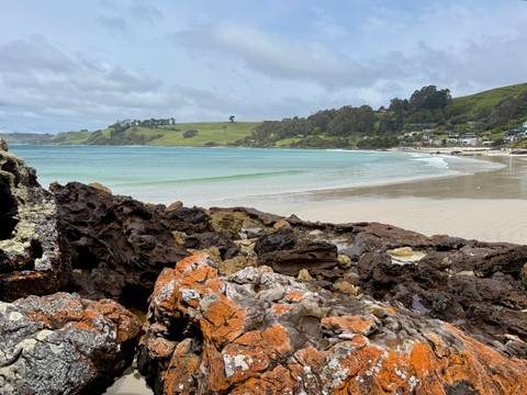       Beach with soft waves and rolling hills in the background.
  