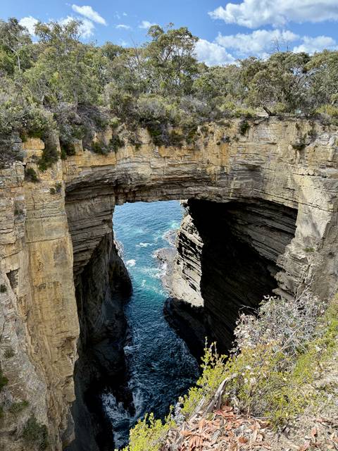       A natural arch formation overlooking the blue ocean.
  