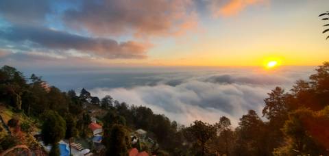 Sunset over a scenic cloudscape with hills in the foreground.