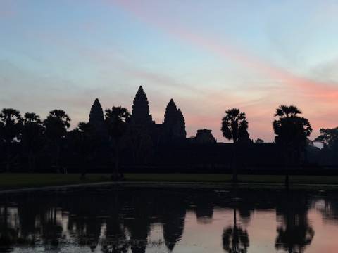 Angkor Wat with colorful sky at sunset, seen across a water body.