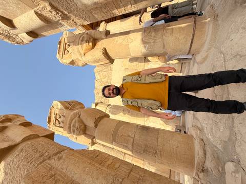      Person standing among ancient pillars.
  