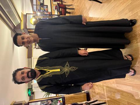       Two people indoors wearing traditional attire.
  