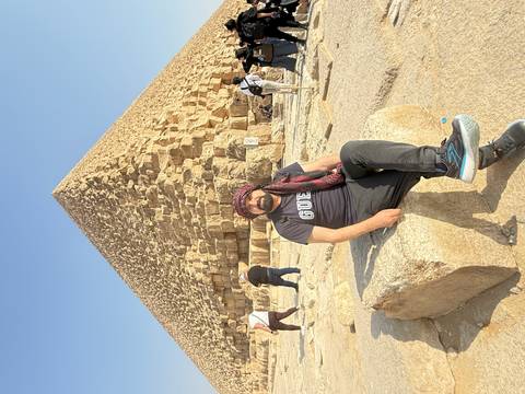       Man sitting in front of a pyramid.
  