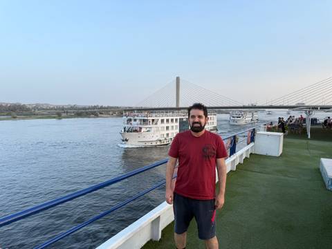       Person on a boat looking at a bridge over a river.
  