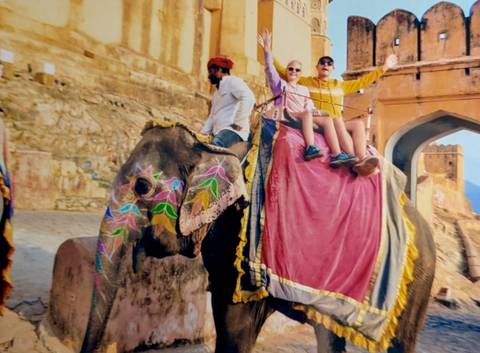 Tourists riding an elephant decorated with colorful cloths and designs.