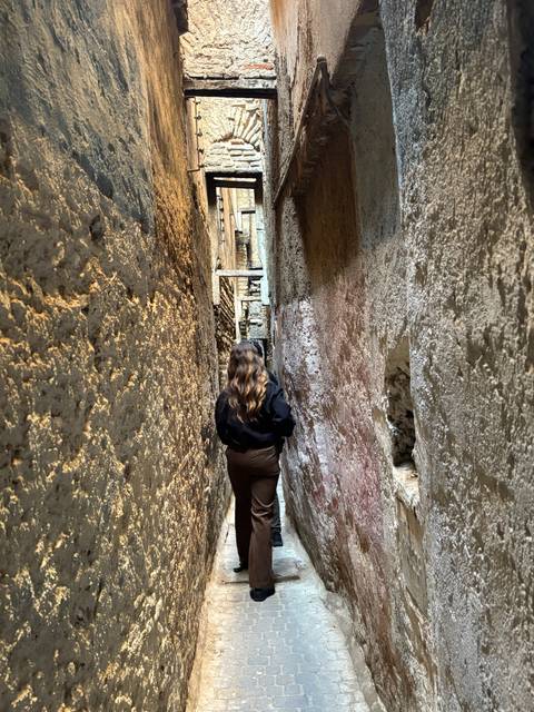       Woman walking through a narrow alley.
  