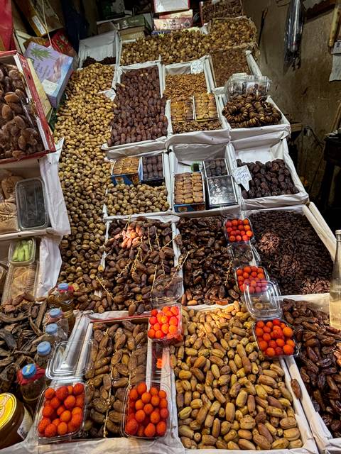       A market stall displaying a variety of dates and dried fruits in a Moroccan market.
  